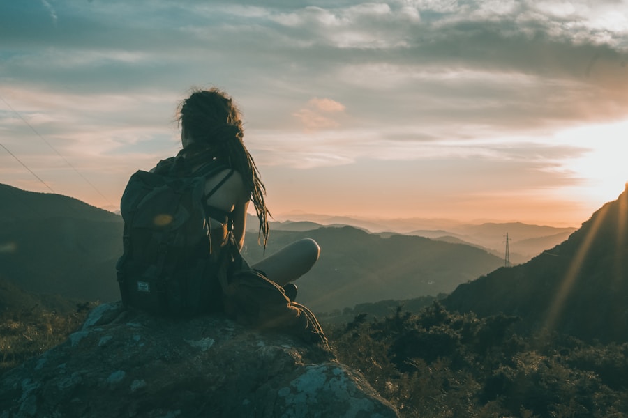 Solo traveler sitting on a rock overlooking a mountain valley at golden hour